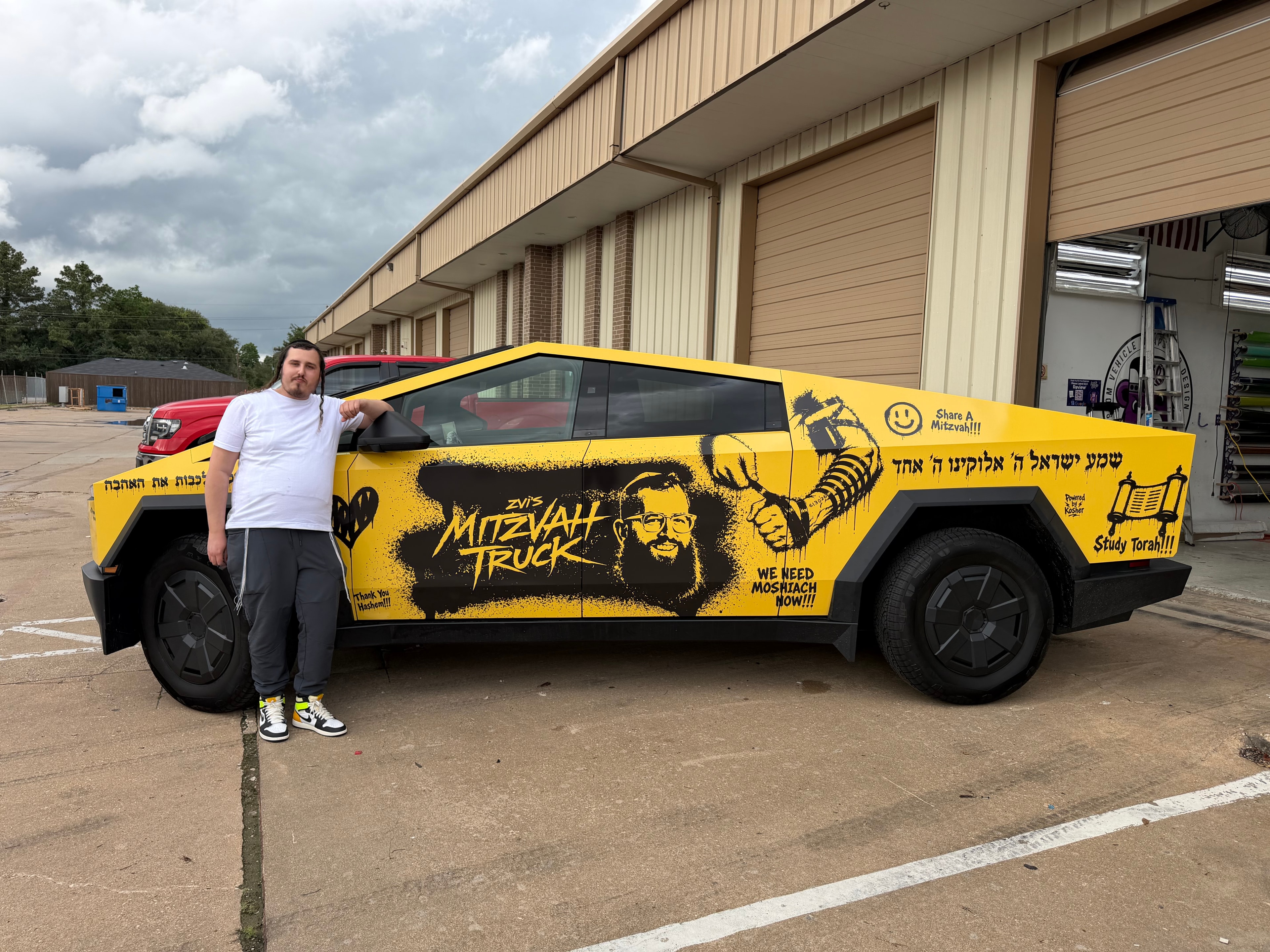 Person standing beside the Mitzvah Truck at a vehicle wrap shop